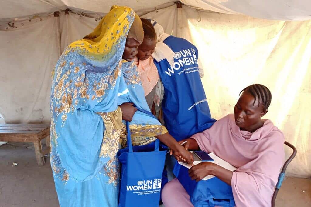 Internally displaced women are seen receiving hygiene kits from a volunteer at a shelter in Port Sudan. Photo: Awoon Organization.
