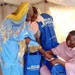Internally displaced women are seen receiving hygiene kits from a volunteer at a shelter in Port Sudan. Photo: Awoon Organization.